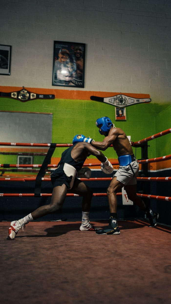 Two athletes spar in a boxing gym, showcasing power and focus.